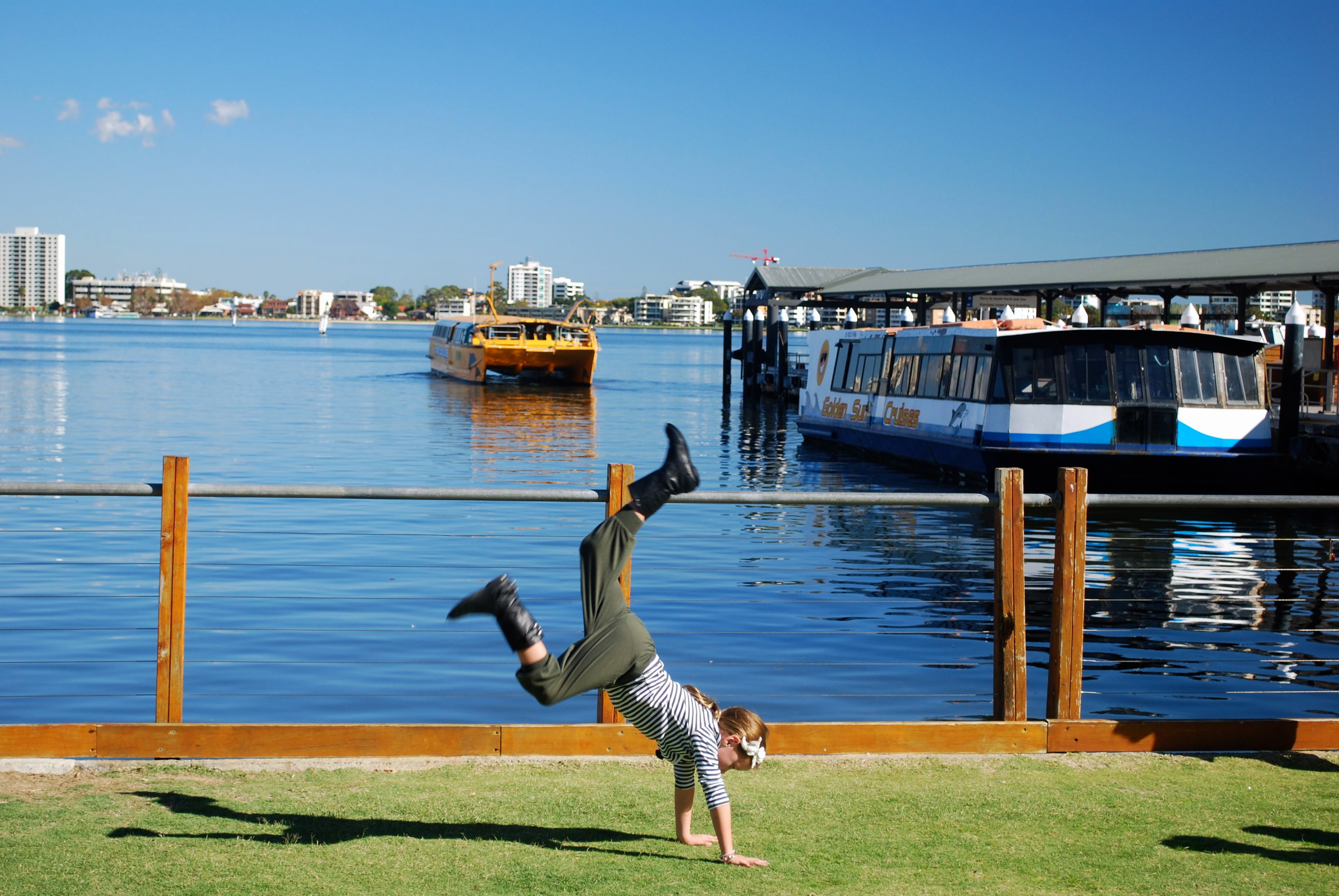 Child doing handstand near Swan River in Perth